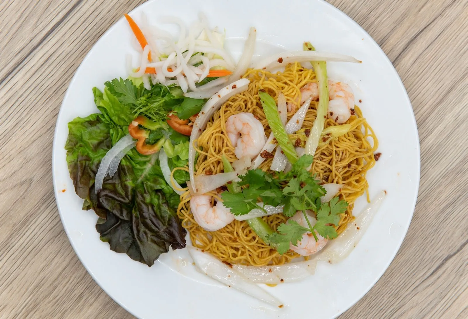 Stir-fried yellow egg noodles topped with cooked shrimp and mixed raw greens at Pho Kitchen, a Vietnamese Restaurant in San Jose